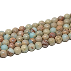 May include: A strand of round, light blue, brown, and beige jasper beads. The beads have a marbled pattern and are approximately 6mm in diameter.