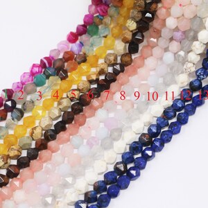 May include: A strand of 13 different gemstone beads, each with a faceted, geometric shape. The beads are arranged in a row, with the numbers 1 through 13 printed below them. The beads are in the following colors: blue, yellow, brown, pink, white, green, and purple.