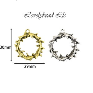 May include: Two metal wreaths, one gold and one silver, with a diameter of 30 mm. The wreaths are made of twisted wire and have a delicate, intricate design.  Lovelybead LLC is printed at the top of the image.