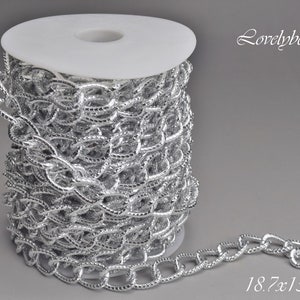 Peut inclure: Une bobine de chaîne argentée de 18,7 x 1,3 x 2,8 mm. La chaîne est en métal et a une finition brillante. Lovelybead LLC est imprimé sur le fond.