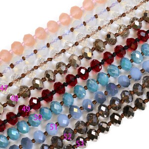 May include: A close-up of eight strands of beaded necklaces with various colors, including light pink, clear, brown, red, blue, and gray. The beads are faceted and have a shiny finish.