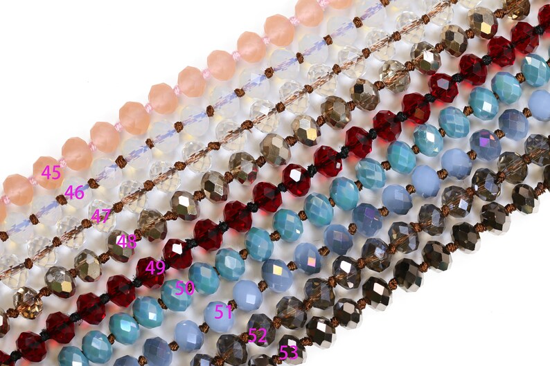 May include: A close-up of eight strands of beaded necklaces with various colors, including light pink, clear, brown, red, blue, and gray. The beads are faceted and have a shiny finish.