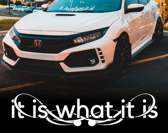Può includere: Una Honda Civic bianca con uno spoiler nero e cerchi neri. L'auto ha un adesivo bianco sul parabrezza che dice "It is what it is".