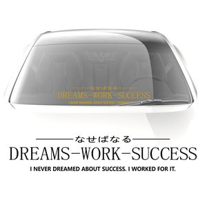 Op de afbeelding: Een witte auto met een sticker op de achterruit met de tekst "なせばなる DREAMS-WORK-SUCCESS I NEVER DREAMED ABOUT SUCCESS, I WORKED FOR IT."