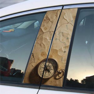 Puede incluir: Calcomanía para ventana de coche con un diseño de mapa vintage y una brújula. La calcomanía tiene un fondo beige con un mapa detallado y una ilustración de brújula. La brújula es de color dorado con marcas negras.