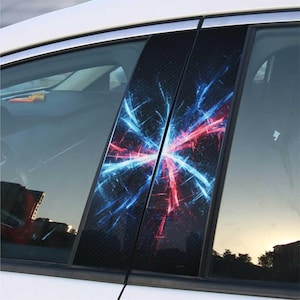 May include: Car window pillar post covers with a carbon fiber texture and a vibrant design. The design features a burst of red and blue lines radiating from a central point. The covers are installed on a white car.