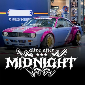 Könnte beinhalten: Ein individuell lackiertes Sportwagen-Modell in Blau und Magenta. Das Fahrzeug hat goldfarbene Felgen und den Schriftzug "alive after MIDNIGHT" in einer stilisierten Schriftart. Auf der Windschutzscheibe steht "PROFI-CAR".