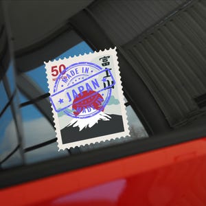 May include: A blue and red stamp with the words "Made in Japan" and a picture of Mount Fuji. The stamp has a white border and a serrated edge.