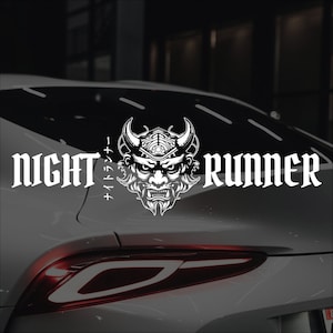 May include: A white car with a black and white sticker on the back window. The sticker features a demon face with horns and the text "NIGHT RUNNER" in a gothic font. The Japanese text "ナイトランナー" is also included on the sticker.