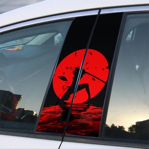 Puede incluir: Calcomanía para ventana de coche en negro y rojo con la silueta de una persona sosteniendo una espada frente a un sol rojo. La calcomanía se coloca en el pilar de la ventana del coche.