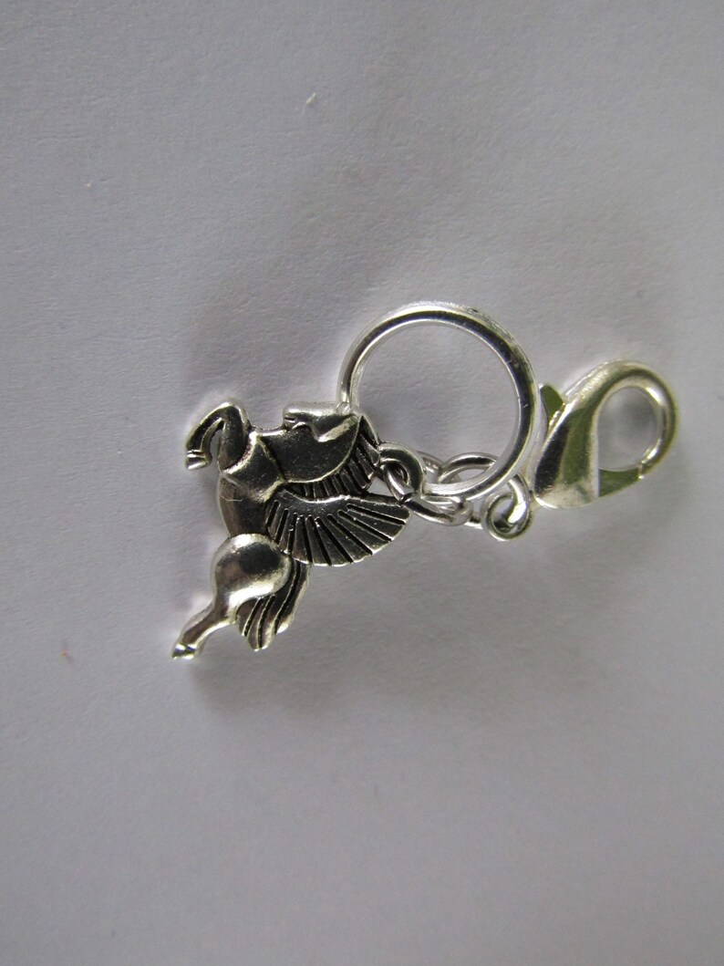 May include: Silver charm featuring a winged horse design with a silver lobster clasp.