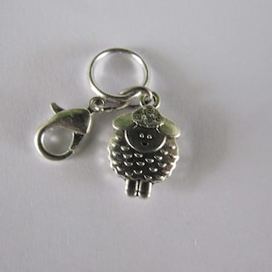 May include: Silver-toned sheep stitch marker with a spring-loaded clasp. The sheep has a curly wool design and a cute face.