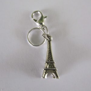 May include: Silver charm featuring a miniature Eiffel Tower with a silver ring and a lobster clasp.