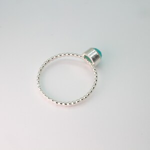 May include: A silver ring with a beaded band and a turquoise gemstone.