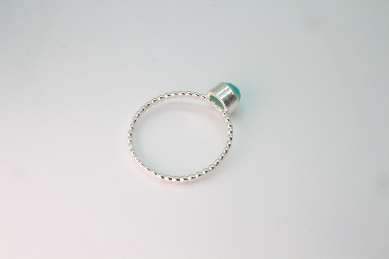 May include: A silver ring with a beaded band and a turquoise gemstone.