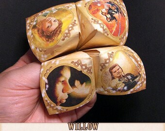 May include: A gold origami fortune teller with images of people and stars. The fortune teller is folded into a cube shape and is being held by a hand. The text "WILLOW inspired Origami Fortune Teller Cootie Catcher. Instant DOWNLOAD." is printed below the fortune teller.
