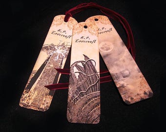 May include: Three vintage-style bookmarks with illustrations and the text "H.P. Lovecraft". The bookmarks feature images of a building, a creature, and a moonlit scene. Each bookmark has a hole at the top with a red ribbon.