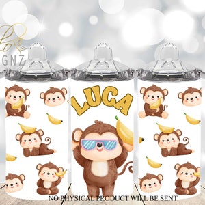 May include: A white stainless steel tumbler with a clear lid and two handles. The tumbler features a repeating pattern of cartoon monkeys holding bananas and a larger monkey wearing sunglasses. The text "LUCA" is printed in yellow on the tumbler.