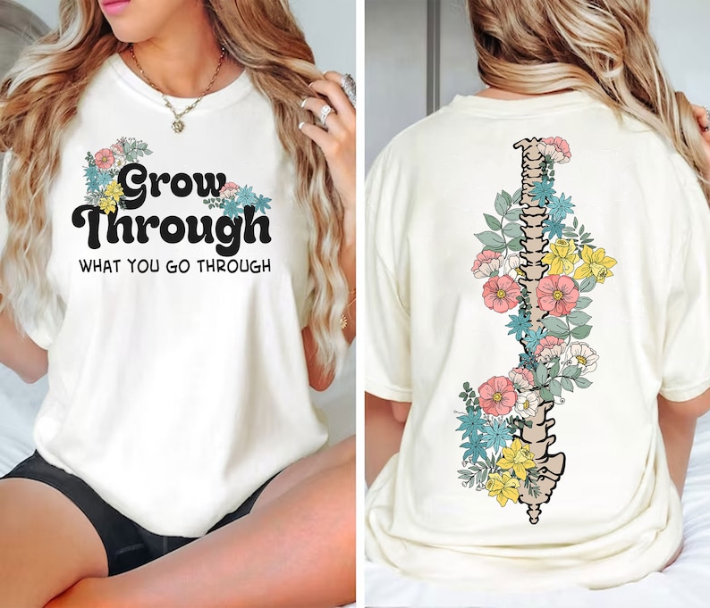 May include: White t-shirt with the text "Grow Through What You Go Through" in black with floral accents. The back of the shirt features a floral design with a spine in the centre.