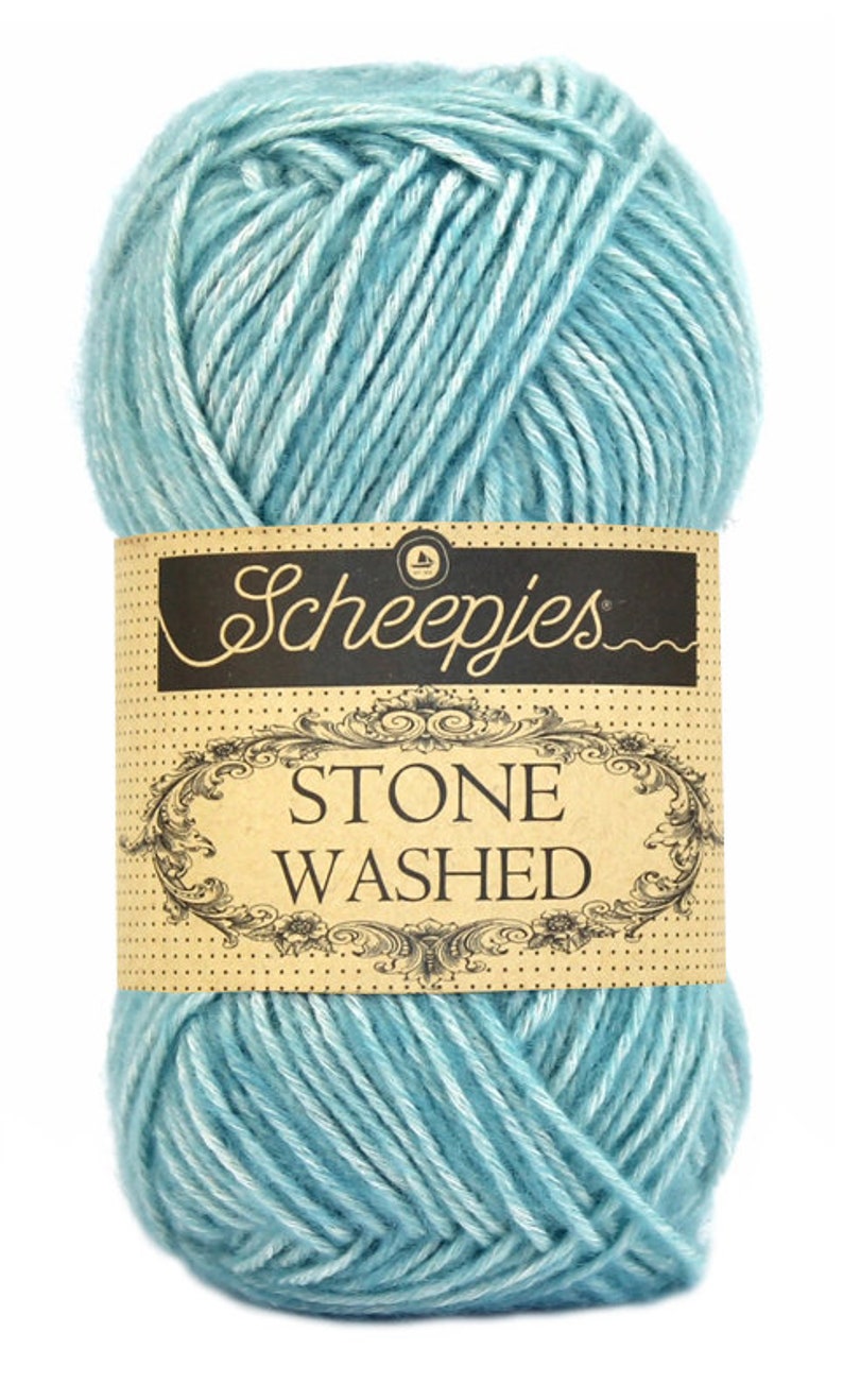 May include: A ball of light blue yarn with white streaks. The yarn is labeled "Scheepjes Stone Washed."