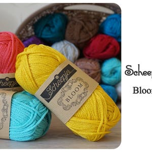 Puede incluir: Primer plano de tres ovillos de hilo en amarillo, turquesa y rosa. El hilo está etiquetado como "Scheepjes Bloom" y es un hilo suave y texturizado perfecto para tejer o hacer crochet.