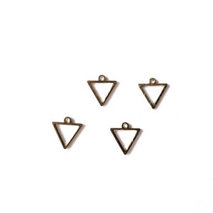 Puede incluir: Cuatro dijes de metal de forma triangular dorada con un bucle en la parte superior.