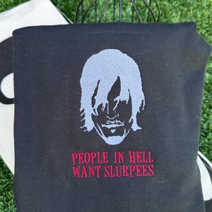May include: Black sweatshirt with a white embroidered image of a man's face and the text "PEOPLE IN HELL WANT SLURPEES" in red.