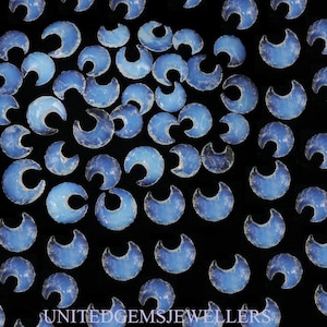May include: A collection of blue crescent moon shaped stones on a black background. The stones are smooth and polished, with a variety of sizes and shapes.