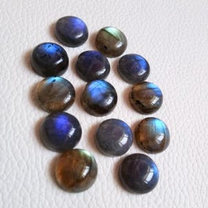 Pu&ograve; includere: Una collezione di 12 cabochon rotondi in labradorite iridescente. Le pietre sono un mix di colori blu, verdi e marroni con una finitura iridescente scintillante.