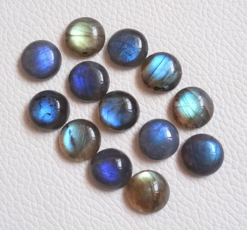 Pu&ograve; includere: Una collezione di 14 cabochon rotondi in labradorite iridescente in tonalit&agrave; di blu, verde e grigio. Le pietre sono lisce e lucidate, con una variet&agrave; di motivi e texture.