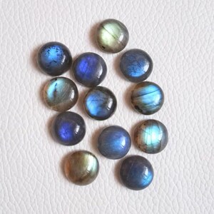Pu&ograve; includere: Una collezione di 12 cabochon rotondi in labradorite iridescente in tonalit&agrave; di blu, verde e oro. I cabochon sono lisci e lucidi, con una variet&agrave; di motivi e texture.