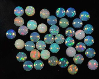 May include: A collection of round, iridescent opal cabochons in various shades of white, blue, and green. The cabochons are approximately 6mm in diameter and have a smooth, polished surface.