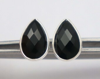 May include: A pair of silver stud earrings with black teardrop-shaped gemstones.