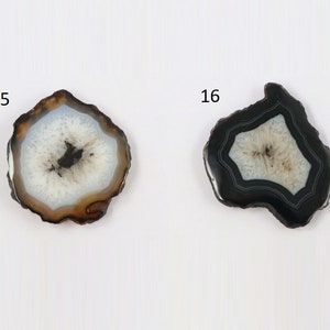 May include: Two agate slices with different patterns. The slice on the left is brown with a white center and black markings. The slice on the right is black with a white center and black markings. Both slices have a rough, natural edge.