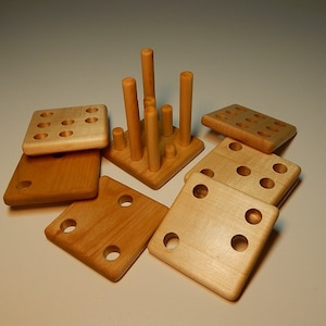 Puede incluir: Un juego de madera con nueve piezas cuadradas y una torre de clavijas de madera. Los cuadrados tienen agujeros y las clavijas encajan en los agujeros. El juego está diseñado para poner a prueba la destreza y la resolución de problemas.