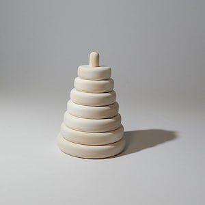 May include: A wooden stacking toy featuring seven rings of varying sizes and a central peg. The natural wood finish gives a simple, classic appearance. This toy is designed for early childhood development and play.