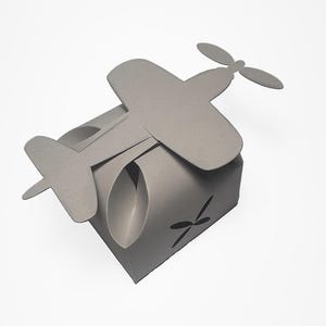 May include: A gray paper airplane-shaped box with a cut-out propeller design. The box is folded flat and ready to be assembled.