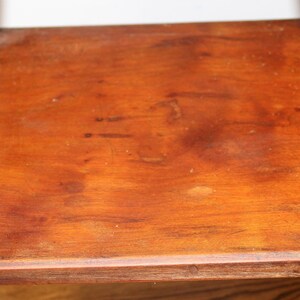 May include: A wooden side table with a square top and turned legs. The table is made of dark wood and has a natural finish.