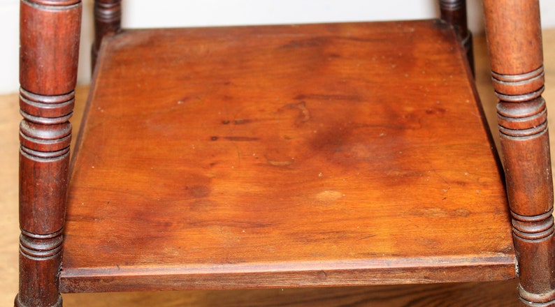May include: A wooden side table with a square top and turned legs. The table is made of dark wood and has a natural finish.