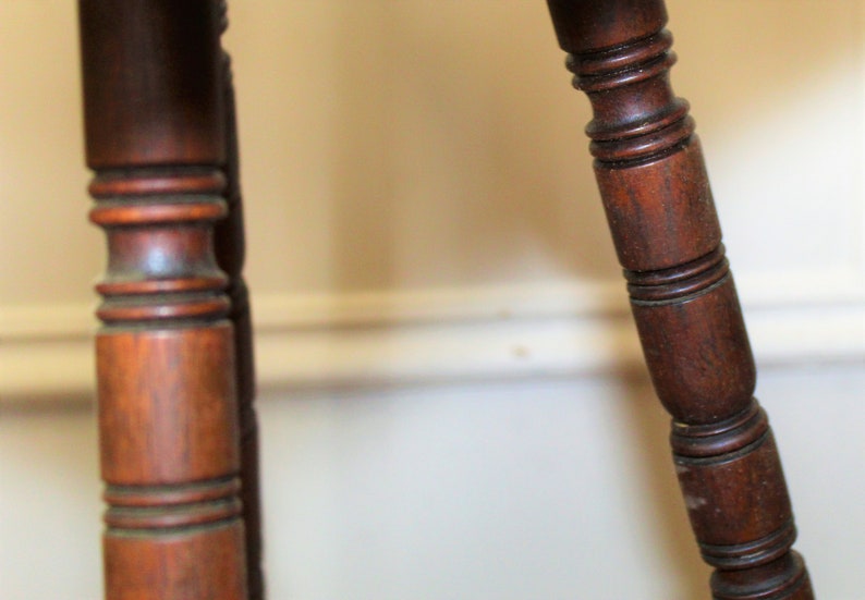 May include: Close-up of two dark brown wooden table legs with intricate carvings. The legs are turned and have a smooth, polished finish.