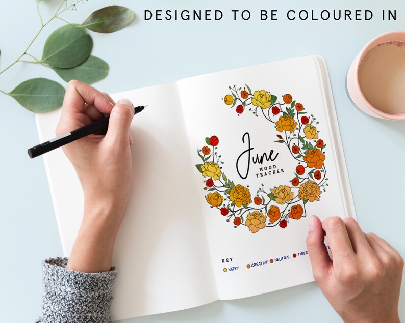 K&ouml;nnte beinhalten: Eine leere Seite in einem Tagebuch mit einem floralen Kranz um das Wort "Juni" und den Text "Stimmungs-Tracker". Die Seite enth&auml;lt auch eine Legende mit vier farbigen Kreisen, die mit "Gl&uuml;cklich", "Kreativ", "Neutral" und "M&uuml;de" beschriftet sind.
