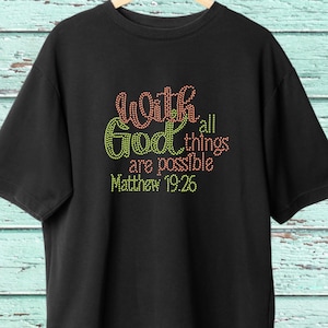 Puede incluir: Camiseta negra con un diseño de pedrería que dice "Con Dios todo es posible Mateo 19:26".