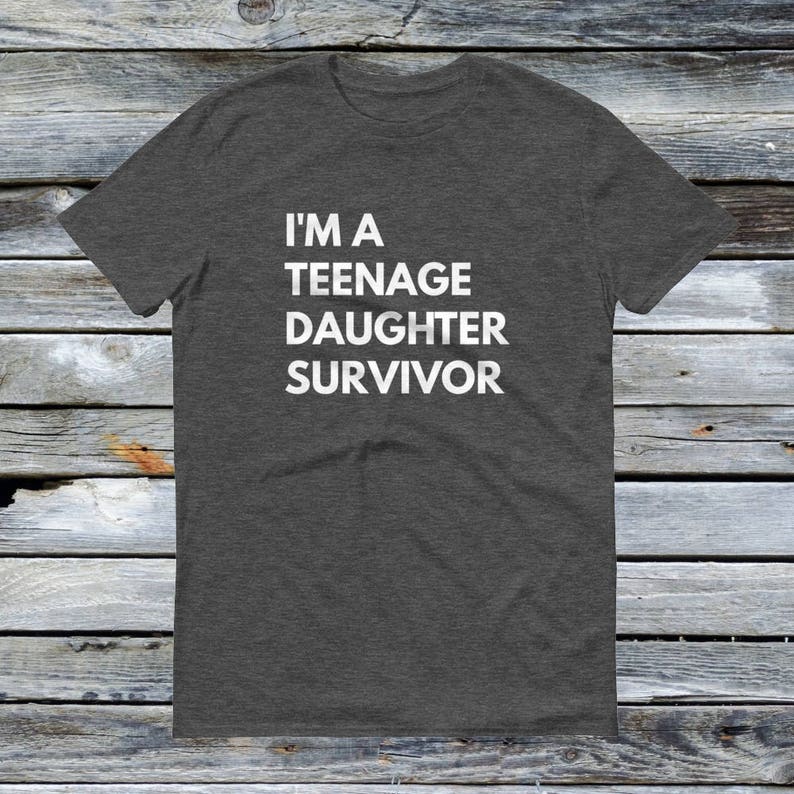 Puede incluir: Una camiseta gris oscuro jaspeada con el texto "I'm a Teenage Daughter Survivor" impreso en blanco.