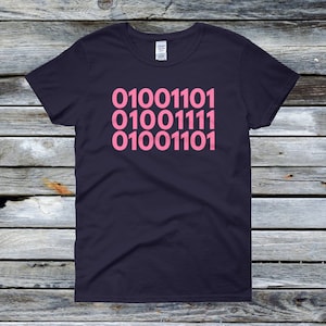 May include: A dark blue t-shirt with a pink design of the binary code "010011101 01001111 010011101" printed on the front.