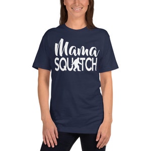 May include: A navy blue t-shirt with white text that reads "Mama Squatch" and a white silhouette of Bigfoot.