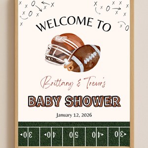 May include: A framed baby shower announcement with a football theme. The text reads "Welcome to Baby Shower" with the names "Brittany & Trevor's" and the date "January 12, 2026". The image includes a football helmet, a football, and a pacifier.