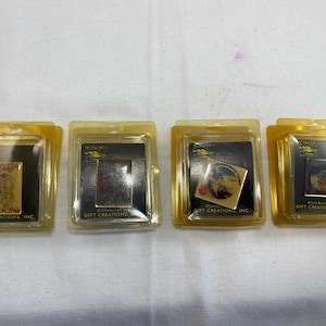 May include: Four small, clear plastic packages each containing a gold-colored pin with a colorful image. The pins are all from the same company, "Gift Creations, Inc."