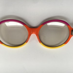 May include: A pair of round, orange, yellow, and pink framed glasses with clear lenses.