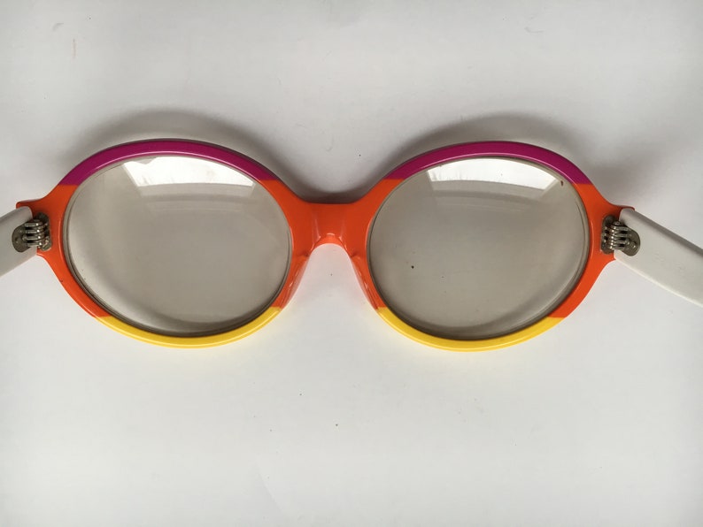 May include: A pair of round, orange, yellow, and pink framed glasses with clear lenses.