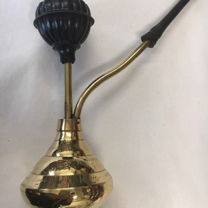 May include: A brass smoking pipe with a black rubber bowl and a wooden stem. The pipe has a decorative design on the base.
